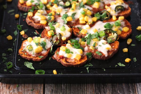 A dark pan with baked sweet potato slices topped with cheese.