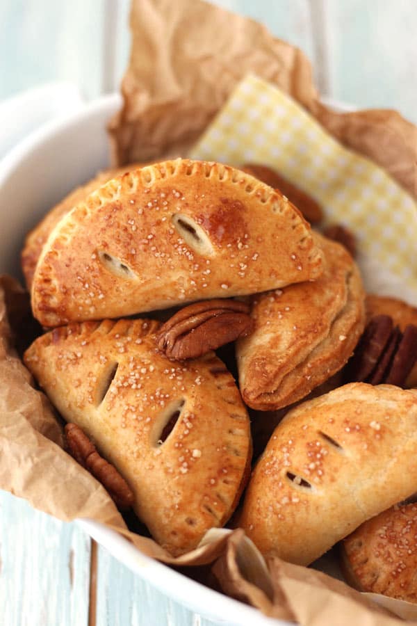 Mini hand pies with pecan halves in a white bowl.