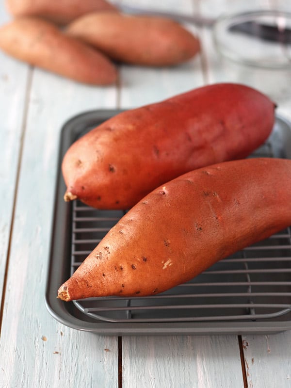 Two sweet potatoes oiled on a pan