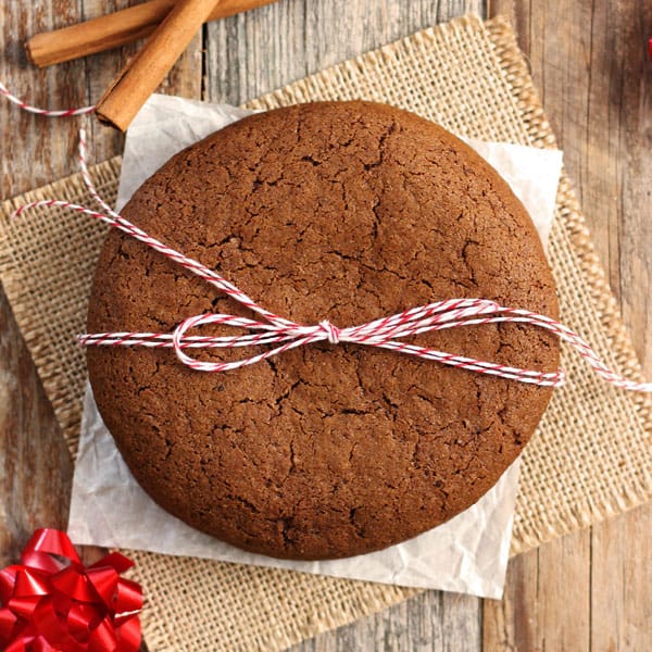 Large molasses cookie tied with red and white string on a wooden table.