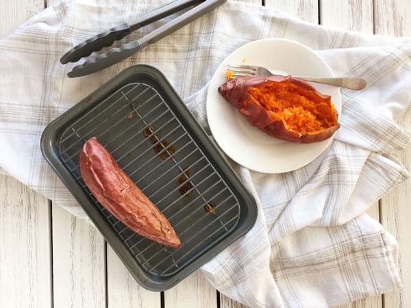 Baked sweet potatoes on a pan and plate with tongs.