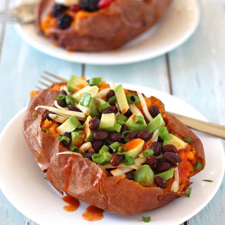Stuffed sweet potatoes on plates on a wooden table.