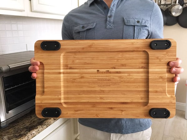 Person holding cutting board showing underside and feet