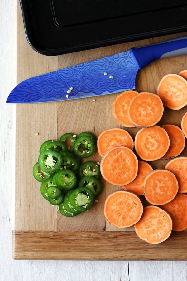 Sweet potato and jalapeno slices on a cutting board.