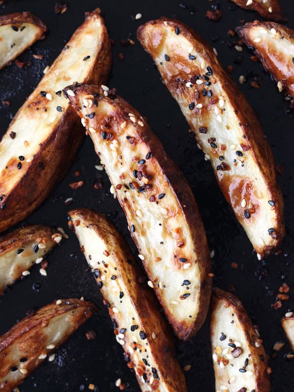 Roasted potato wedges on a dark roasting pan.