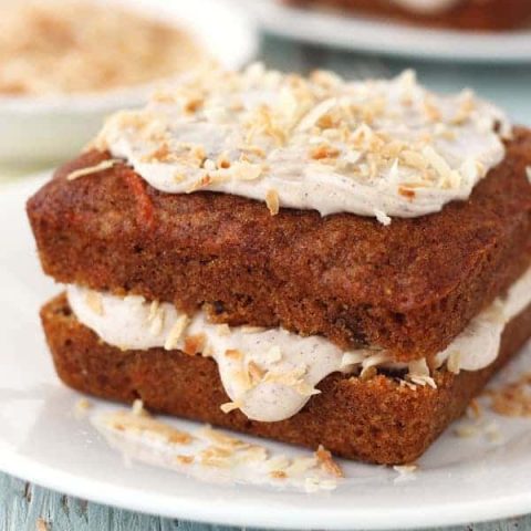 Mini square carrot cakes topped with frosting and toasted coconut.