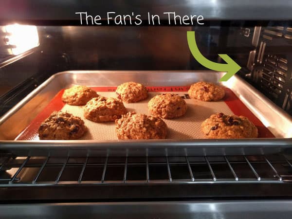 Pan of cookies baking inside a toaster oven with arrow pointing to the convection fan.