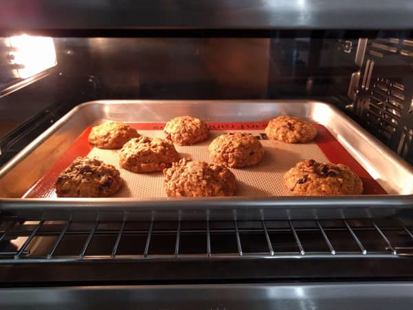 Cookies baking on a sheet pan inside a toaster oven.