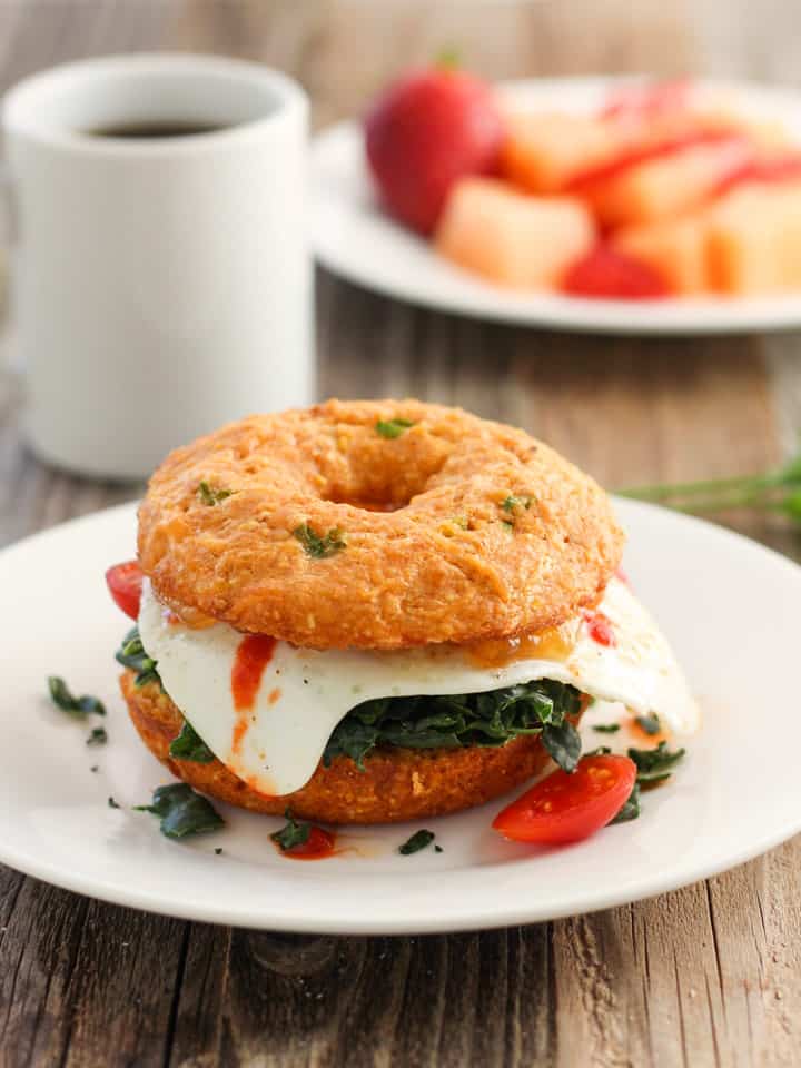 Fried egg between two sides of cornbread donuts with a cup of coffee.