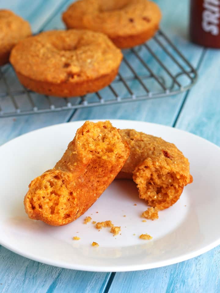 Cornbread donut broken in half on a plate.