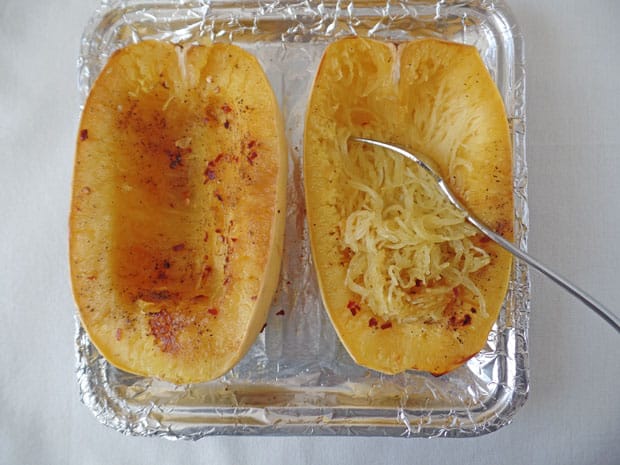 Spaghetti squash halves on a baking sheet covered in foil. 