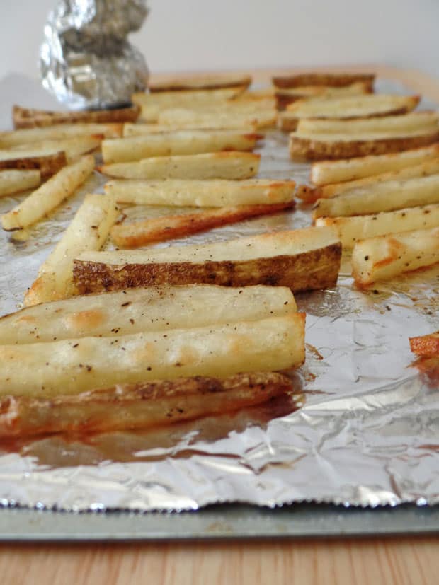 Baked fries on a foil-lined pan.