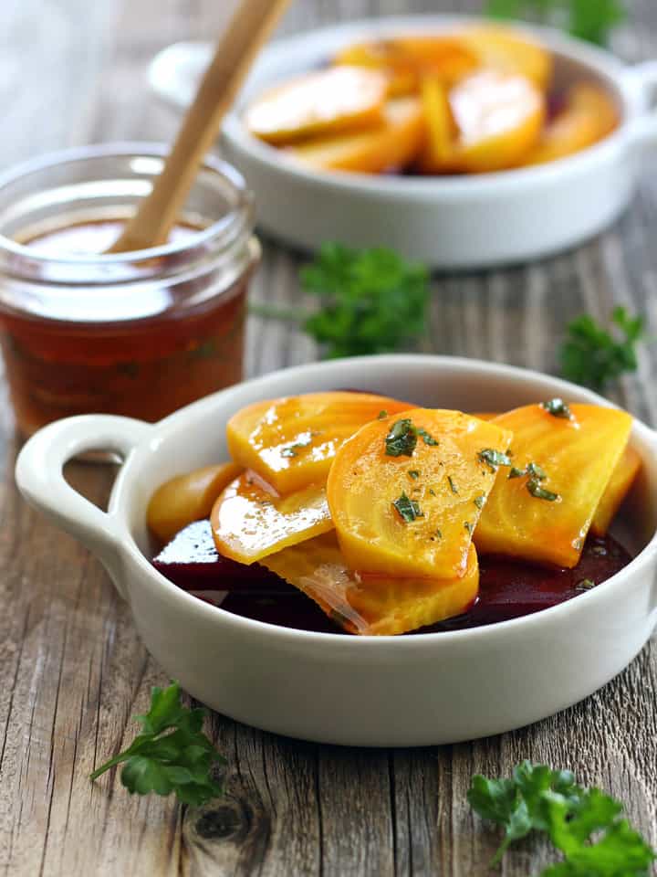 Baked red and yellow beets in white dishes.