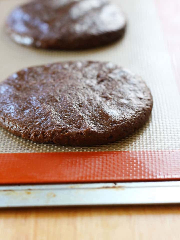 Cookie dough balls pressed onto a silicone baking mat.