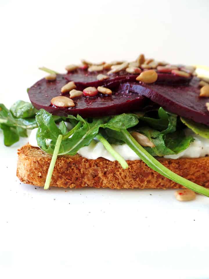 Slice of toast topped with cottage cheese, arugula, and cooked beets.