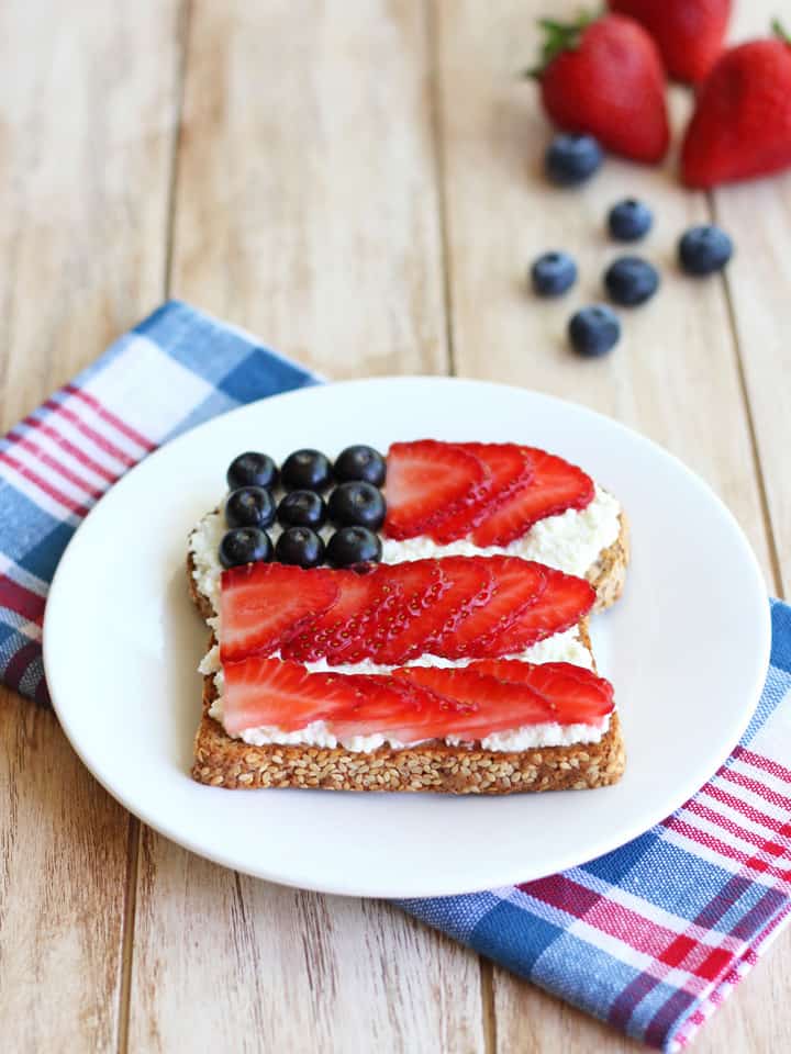 Berry topped toast on a white plate with a blue and red napkin.