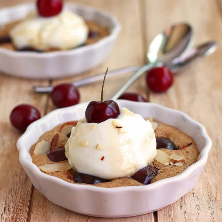 Mini dish of baked cherry cake with a scoop of yogurt and cherry.