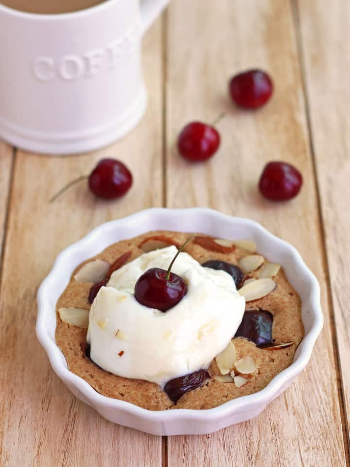 Small cherry breakfast cake with yogurt next to a cup of coffee.