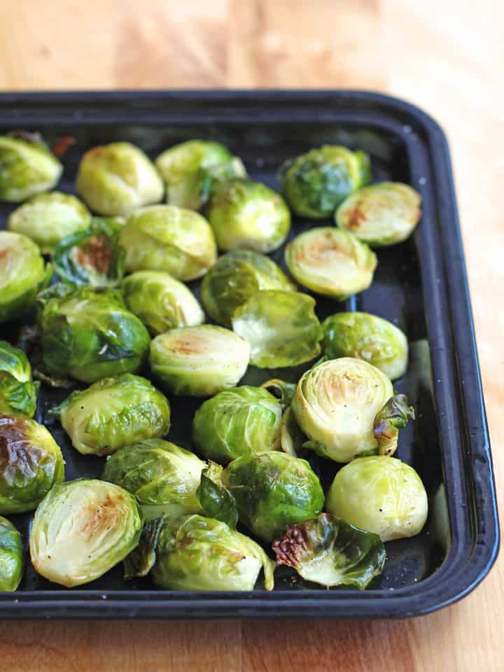 Roasted Brussels sprouts on a small black pan.