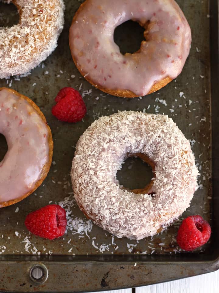 Baked donuts and fresh raspberries on a metal baking sheet