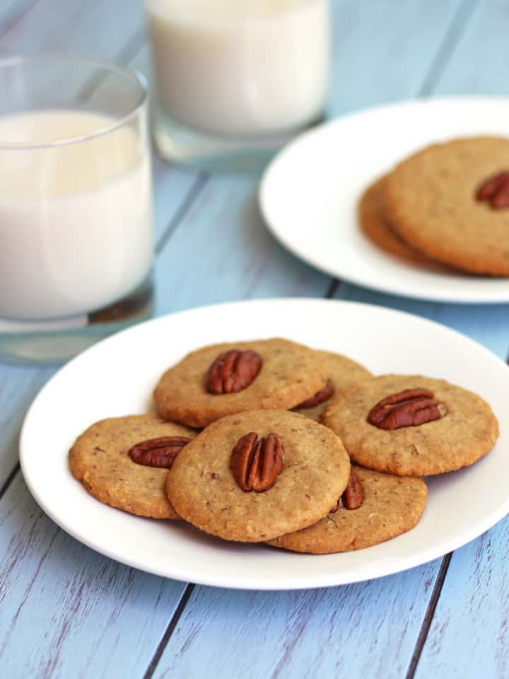 A white plate with cookies next to a glass of milk.