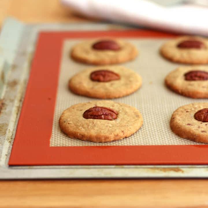 Crispy cookies cooling on a baking mat lined sheet pan.