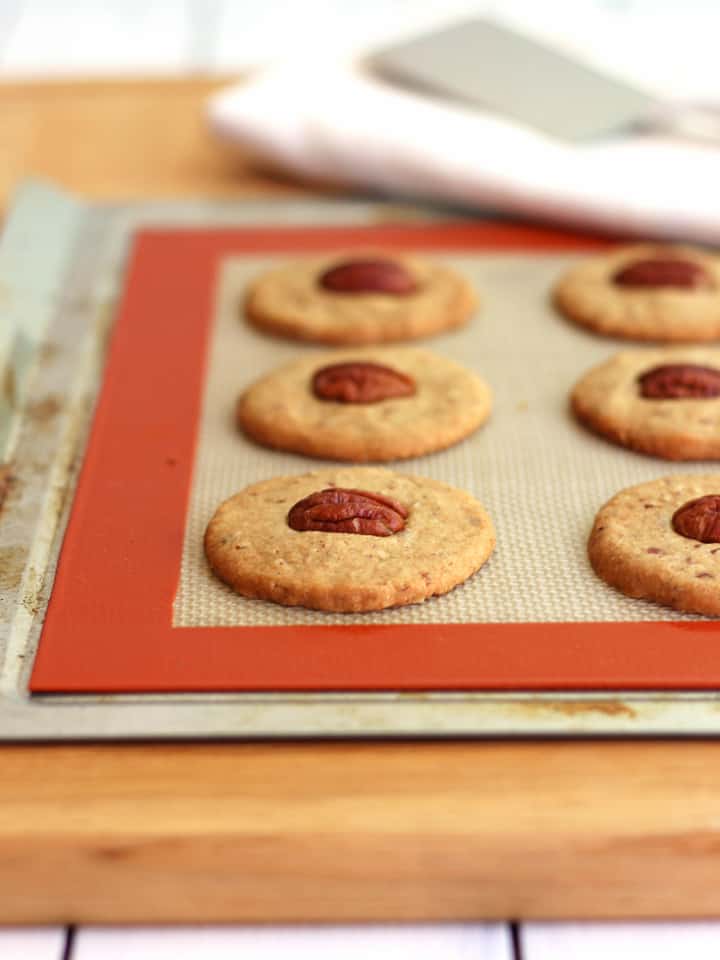 Crispy cookies cooling on a baking mat lined sheet pan.