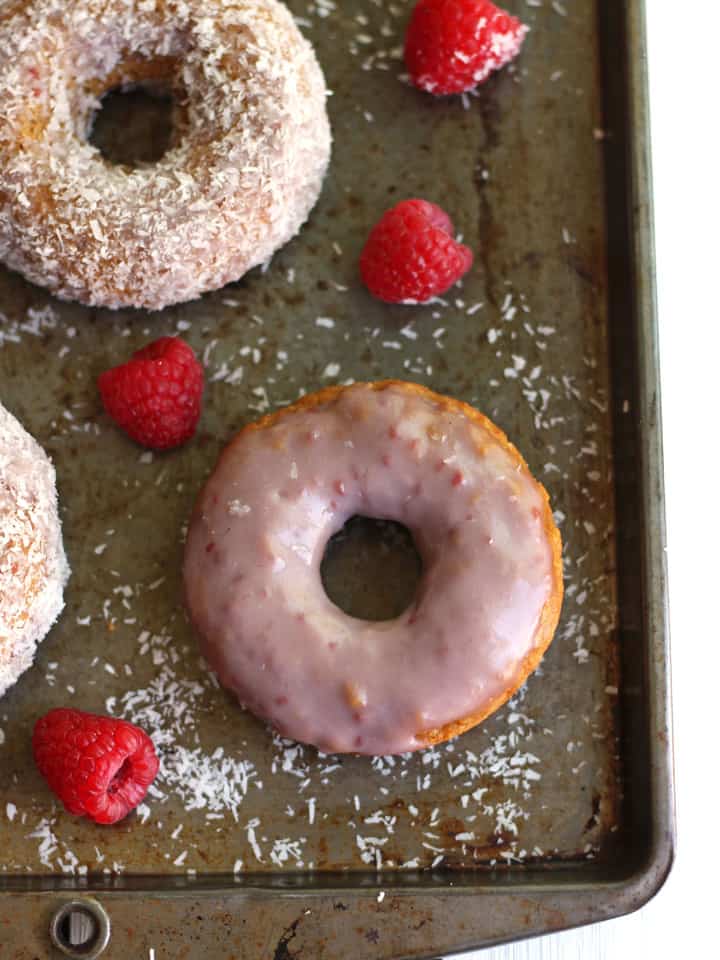 Overhead view of raspberry coconut donuts on baking sheet. 