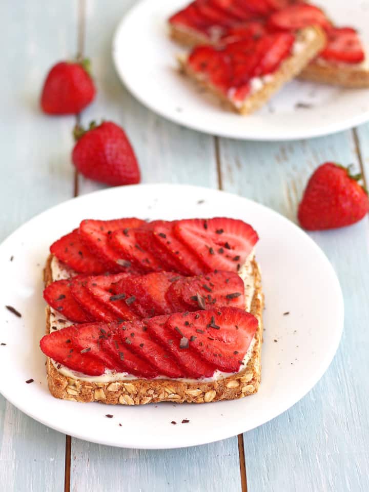 Toasts topped with rows of sliced fresh strawberries.