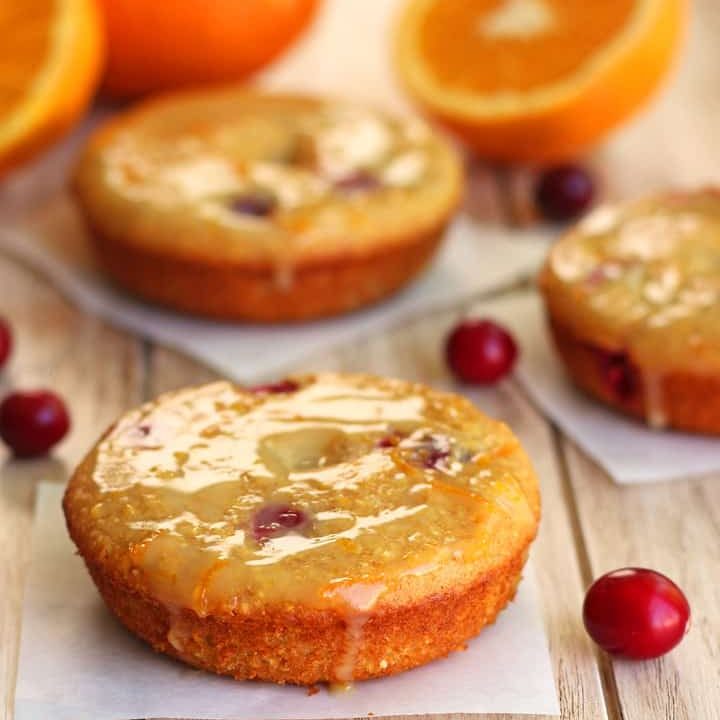 Baked cranberry cornbread donuts on squares of parchment paper.