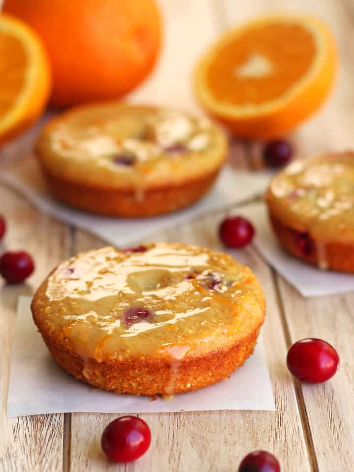 Baked cranberry cornbread donuts on squares of parchment paper.