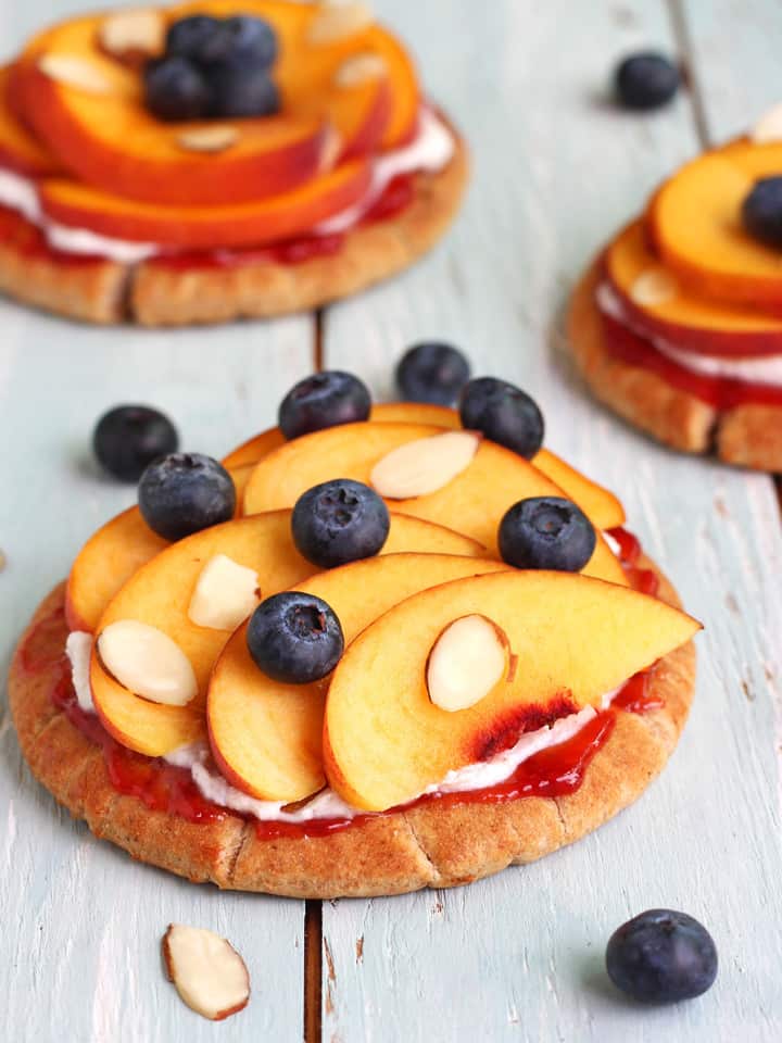 Pitas topped with ricotta, peach slices, and fresh blueberries.