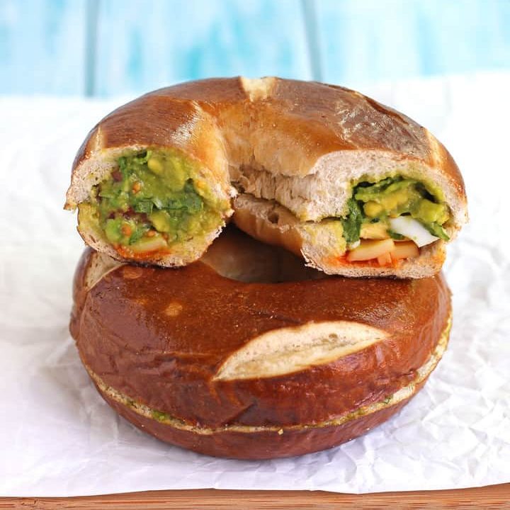 Bagel sandwiches stacked on a cutting board.