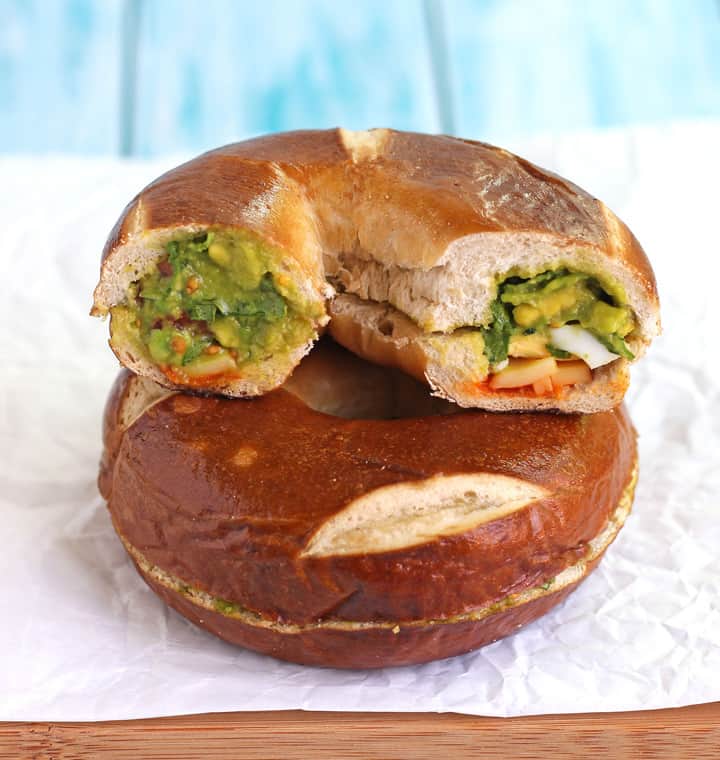 Bagel sandwiches stacked on a cutting board.