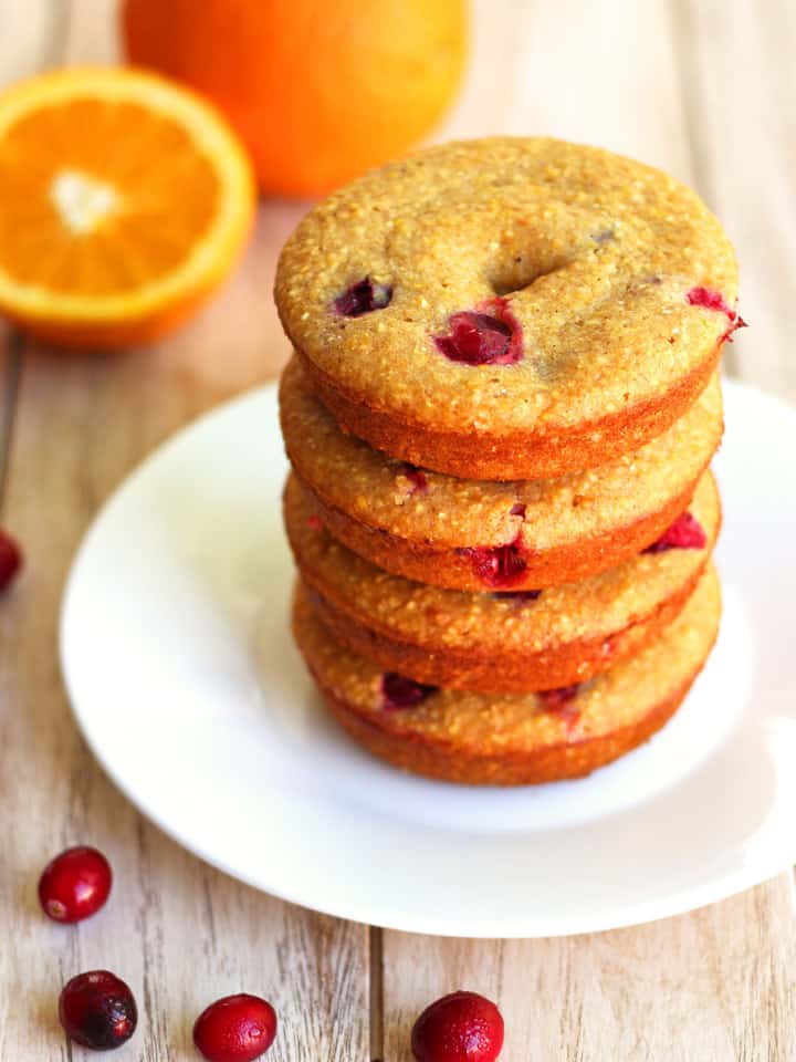 Stack of baked cranberry cornbread donuts on a white plate.