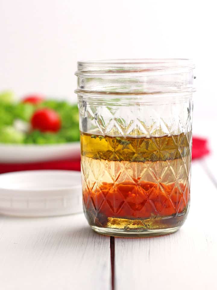 Mason jar with oil, vinegar, and sriracha sauce.