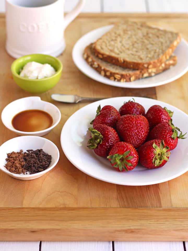 Plate of whole strawberries with small bowls of mascarpone cheese, espresso, and chocolate.
