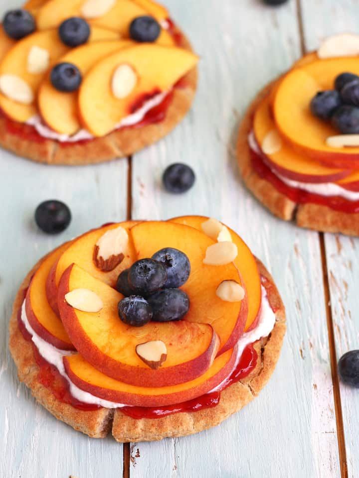 Toasted pitas topped with peach slices and fresh blueberries.