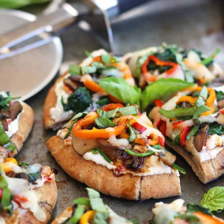 Mini pizza bites on a sheet pan with a pizza cutter.