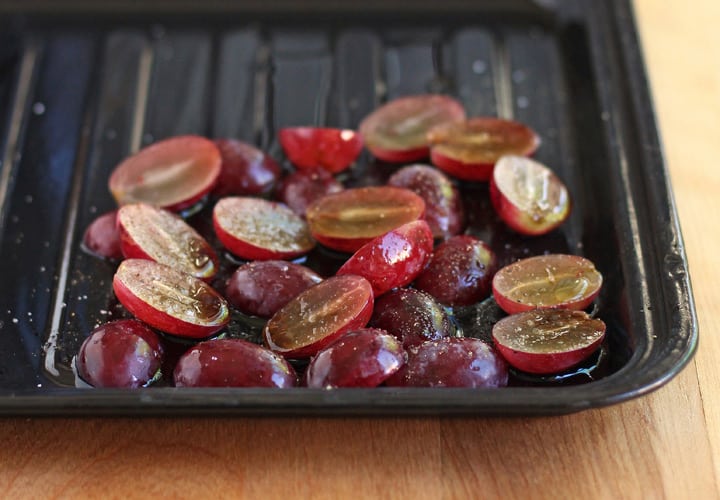 Dark roasting pan with sliced grapes.