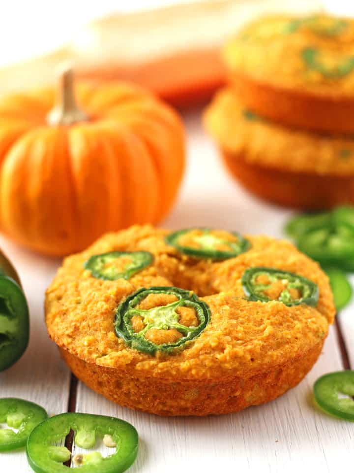 Baked cornbread donuts on a white table with a mini pumpkin.