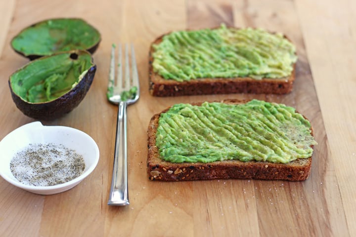 Avocado mashed on toast with a fork.