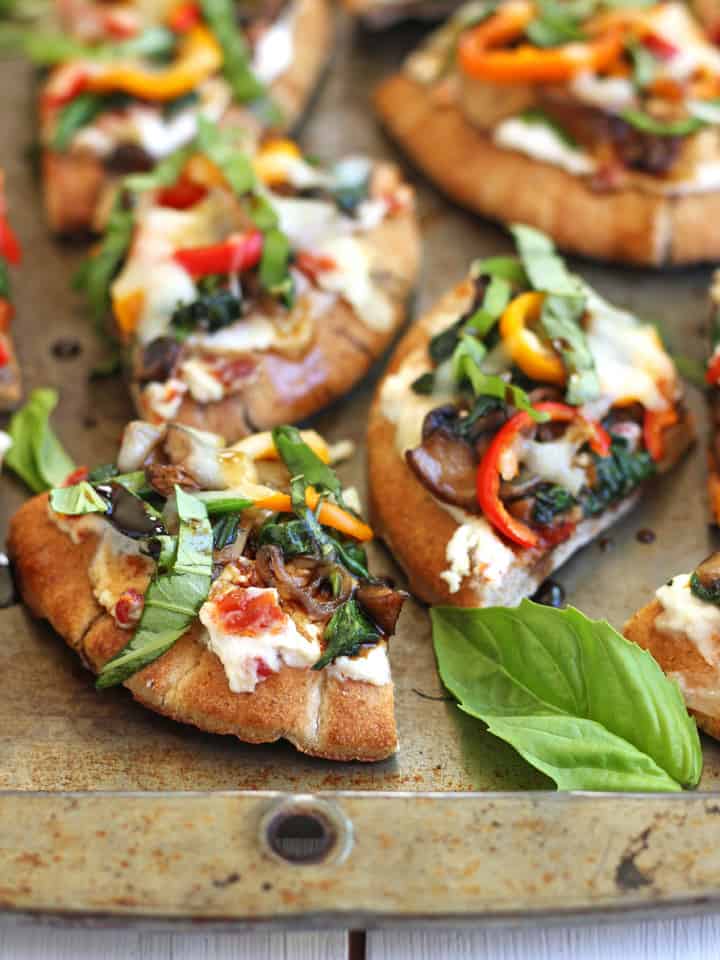 Sheet pan of pita pizza slices and fresh basil leaves.