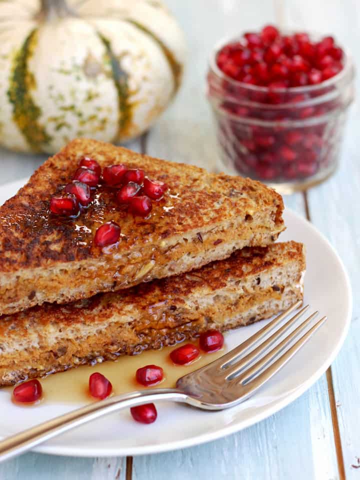 Stuffed french toast slices stacked on a plate drizzled with maple syrup.