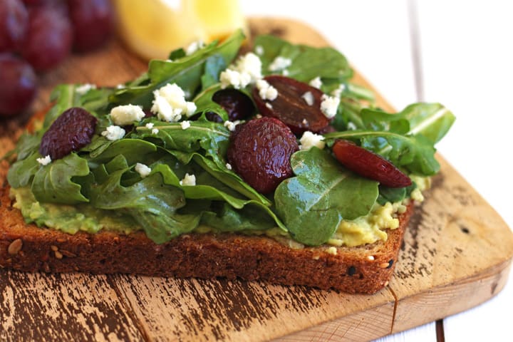 Closeup of balsamic roasted grapes on a slice of avocado toast.