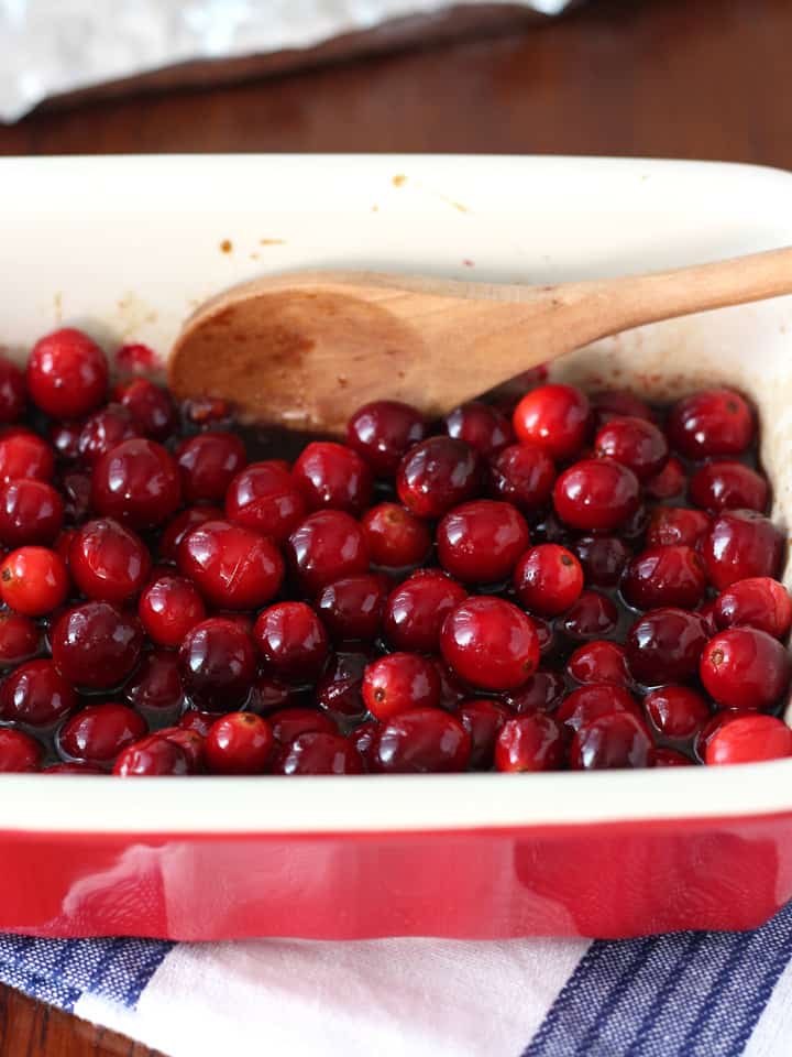 Wooden spoon stirring roasted cranberries.