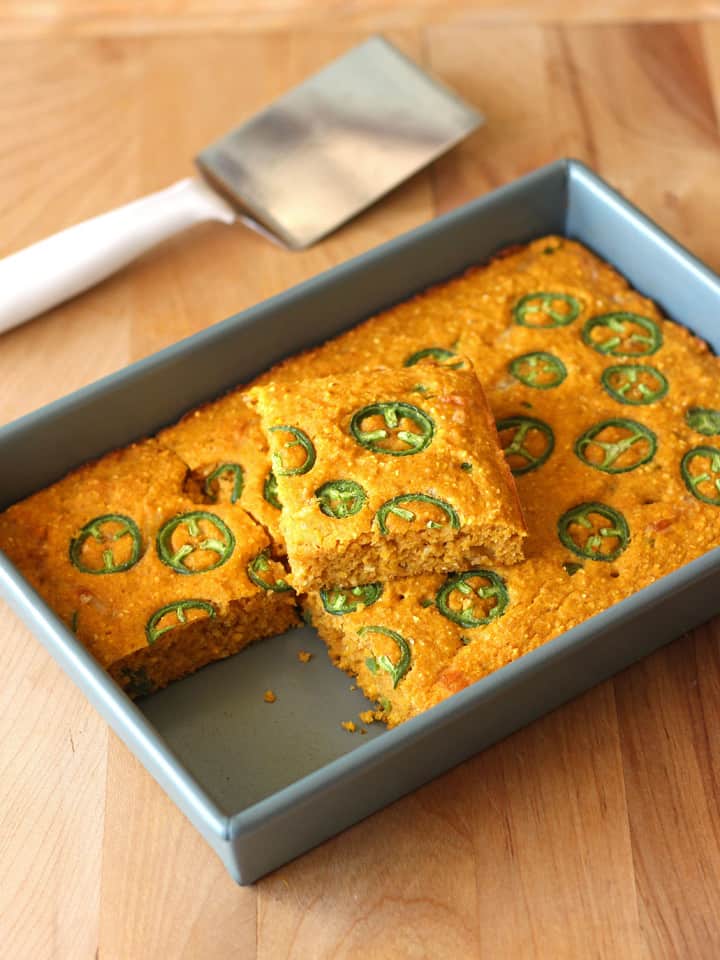 Jalapeño Pumpkin Cornbread in an 11 x 7 metal pan on a cutting board.