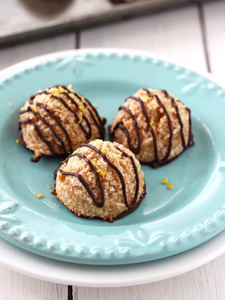 Chocolate drizzled macaroon cookies on a plate.