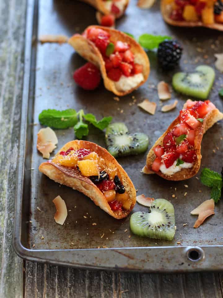 Sheet pan of fruit tacos with fresh raspberries and kiwi cut out hearts.