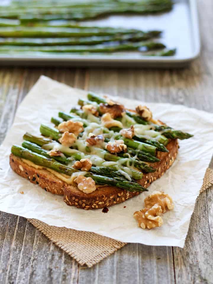 Piece of toast topped with hummus and asparagus.